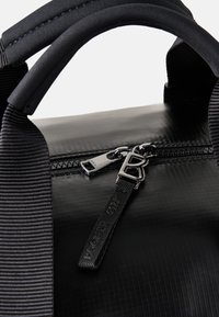 Czarna torba z zamkiem błyskawicznym, charakteryzująca się gładkim, teksturowanym wykończeniem, wytrzymałą tkaniną oraz grubym nylonowym uchwytem z kontrastowymi przeszyciami.