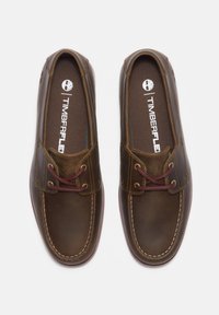 Bruna läderskor med en slät yta, kontrasterande sömmar och bordeauxfärgade snören. Har en logo på insulan och en klassisk design.