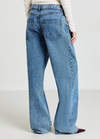 Jeans a gamba larga, chiari e a vita alta, con una finitura scolorita, due tasche posteriori e un tessuto denim morbido e testurizzato.