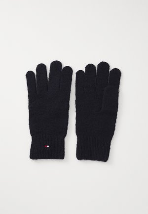 Coppia di guanti neri lavorati a maglia con polsini a coste e piccolo logo a bandiera rosso, bianco e blu su un polsino, disposti su sfondo bianco.