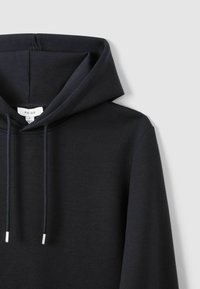 Hanorac închis navy, dintr-un material moale, cu un glugă mare, șnururi frontale cu vârfuri argintii și un design minimalistic.