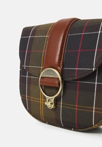 Mala crossbody em padrão xadrez castanho com alça de couro e acabamentos em dourado. Apresenta um aba arredondada e um fecho metálico proeminente com o nome da marca.