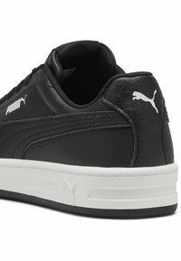 Must musta tossud mustade nahast sneakersitega tekstuuriga viimistlusega, valge tallaga ja väljapaistva Puma logoga külje ja tagaosas. Sujuv lingisüsteem.