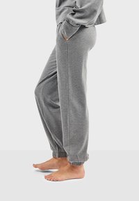 Pantalones deportivos grises con un corte relajado, puños elásticos y bolsillos laterales. Tejido suave con una textura lisa, adecuado para el uso casual.