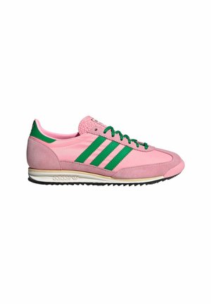 Niski but Adidas w kolorze różowym z zielonymi paskami, zielonymi sznurówkami, zamszowym noskiem i żebrowaną czarną podeszwą.