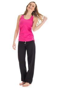Pink athletic tank top with racerback design, paired with loose-fitting black pants made of soft fabric. No patterns or logos visible.