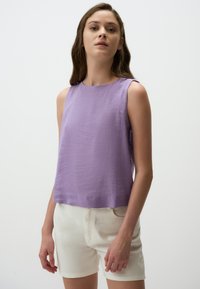 Lila mouwloze top met een ronde halslijn, gemaakt van textuurstof; gecombineerd met witte shorts met een minimalistisch ontwerp.