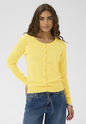 Żółty dziany kardigan z okrągłym dekoltem, długimi rękawami oraz zapinany na guziki przód z sześcioma pasującymi guzikami. Gładka faktura.