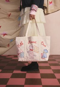 Drobelė rankinė šviesiai rožinės spalvos su šunų iliustracijomis ir spalvotais patchwork dizainais. Tvirti rankenėlės, stačiakampio formos ir grafiškas tekstas.