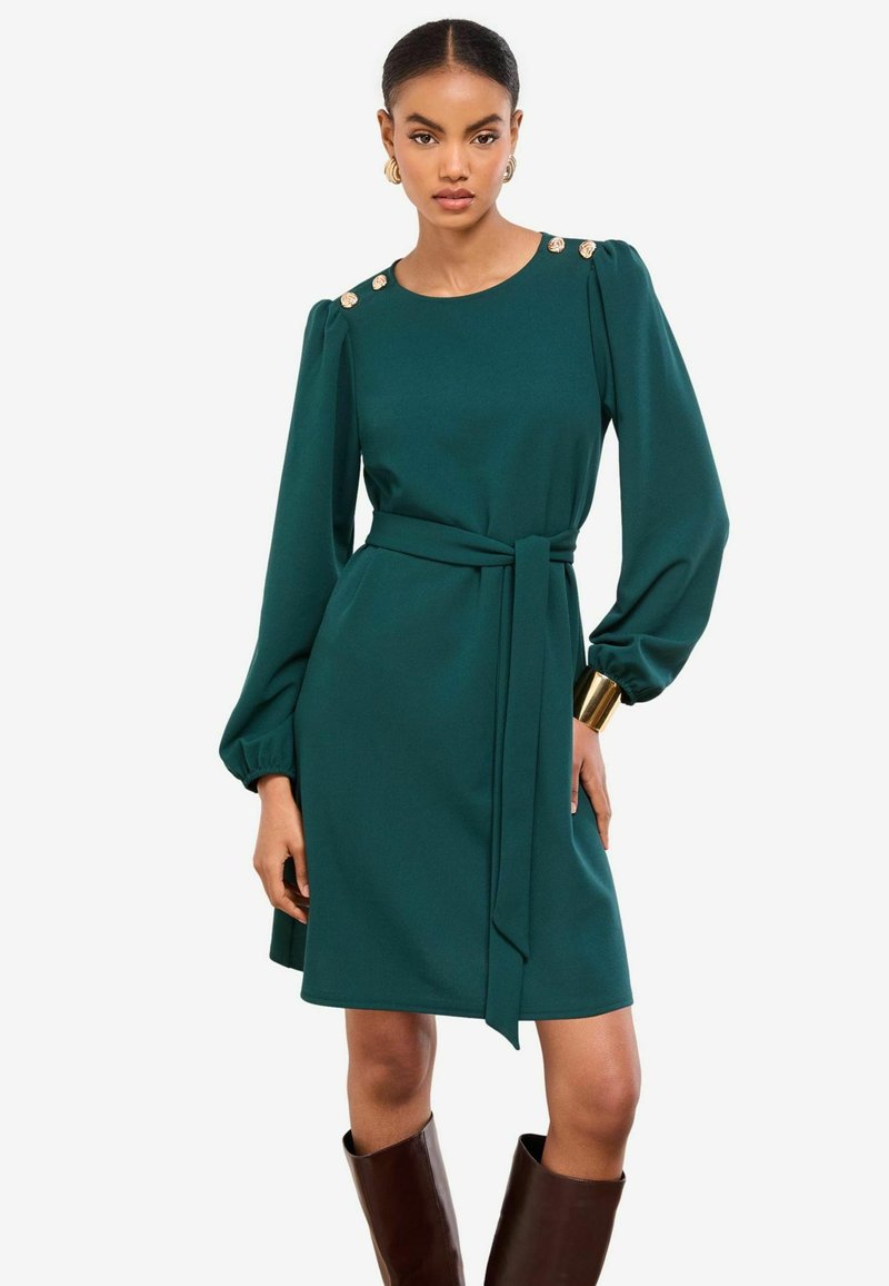 Tyrkysové šaty s dlhými nadýchanými rukávmi, zoštíhleným pásom a zlatými gombíkmi na pleciach. Hladká látka a dĺžka po kolená.