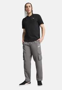 Black short-sleeve T-shirt and gray cargo pants with side pockets, paired with black sneakers featuring a pink accent.
