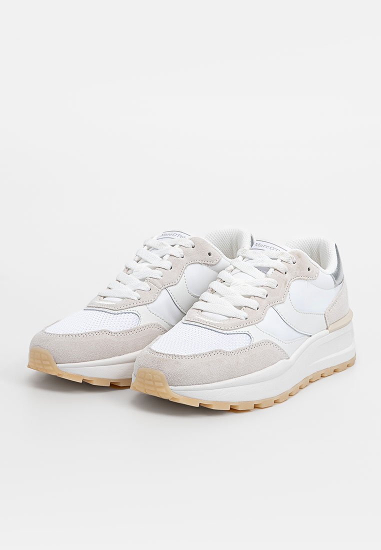 Une paire de baskets blanches et beiges avec des détails en maille et en daim, un design à lacets et des semelles en caoutchouc gomme sur un fond blanc uni.