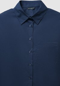 Camicia abbottonata blu navy realizzata in tessuto liscio, con colletto a punta, sei bottoni e taschino sul lato sinistro.