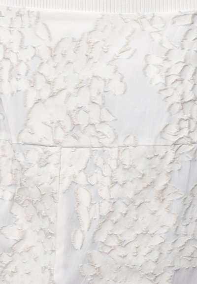 Λευκό ύφασμα με ανυψωμένο λουλουδένιο κέντημα και οριζόντια ραφή στη μέση.