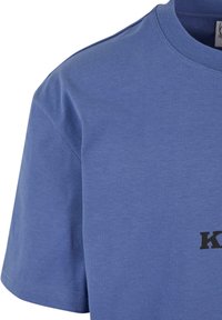 Trumpa rankovė T-shirt švelnios mėlynos medvilnės, su apvaliu kaklu ir juodu spausdintu logotipu priekyje. Lygus paviršius ir standartinė forma.