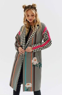 Długi płaszcz we wzór houndstooth z żywymi kwiatowymi akcentami, z poziomymi paskami w kolorach różowym, pomarańczowym i teal. Wykonany z teksturowanej tkaniny.