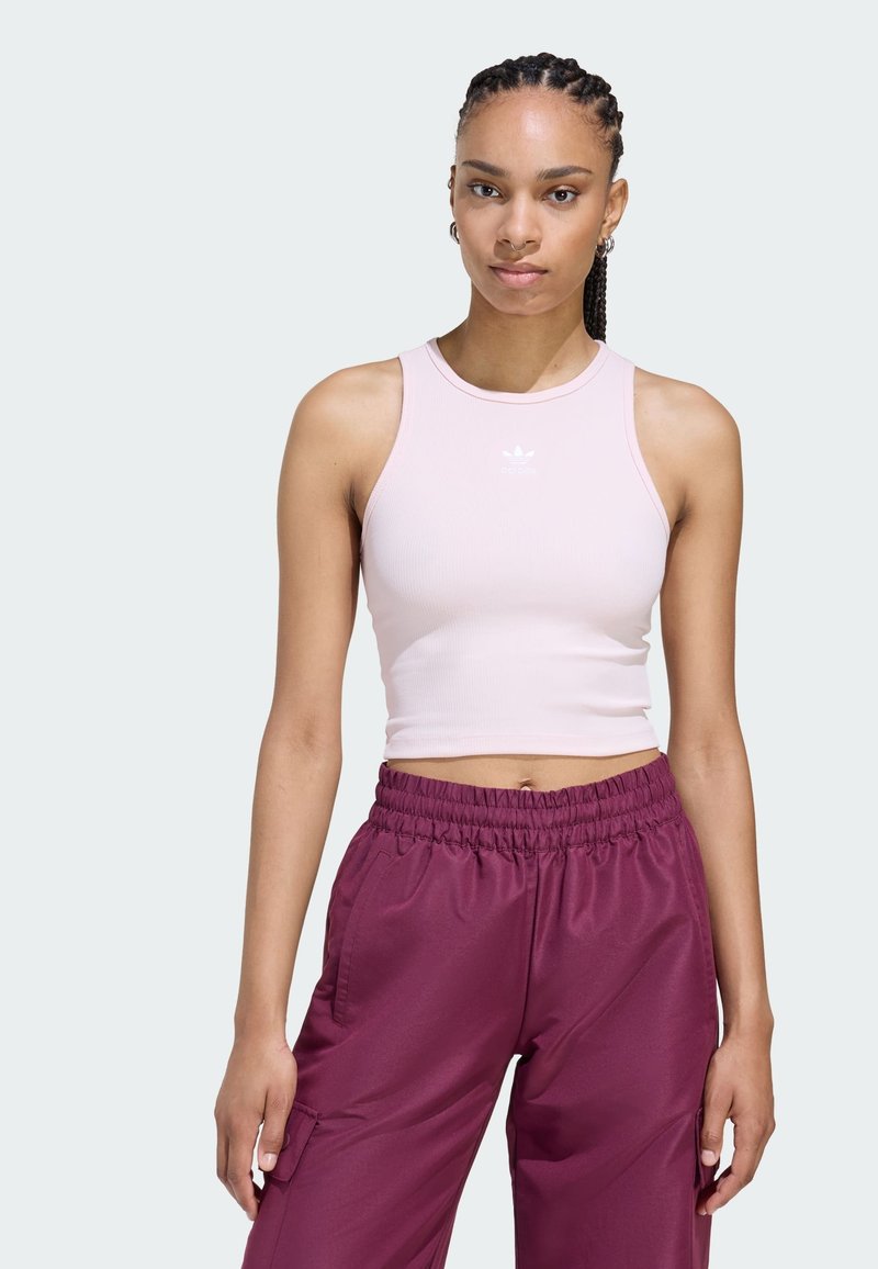 Ružový rebrovaný crop top s okrúhlym výstrihom a bielym logom, spárovaný s marhuľovými cargo nohavicami na gumu s bočnými vreckami.