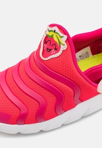 Rosa sportskor med ett strukturerat meshovansida, med en leende jordgubbsapplikation på tungan och en vit gummisula.