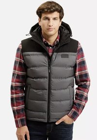 Szary kamizelka puchowa z czarnymi ramionami, z zapięciem na zamek i kieszeniami, nałożona na czerwoną koszulę w kratę. Gładka faktura z wyściełanymi sekcjami.