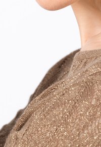 Gegolfde, glanzende bruine stof met ingewikkelde golvenpatronen hangt over de schouder en benadrukt de lichte, semi-transparante kwaliteit.