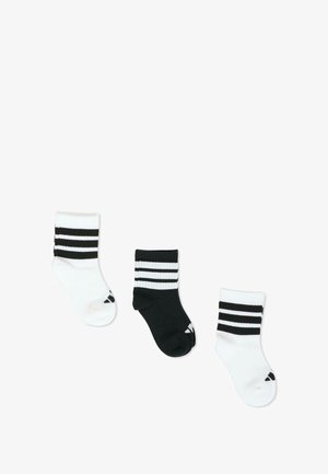 Drei Paar Knöchelsocken: ein schwarzes mit weißen Streifen, zwei weiße mit schwarzen Streifen. Weiche, gerippte Textur, Mischgewebe aus Baumwolle.