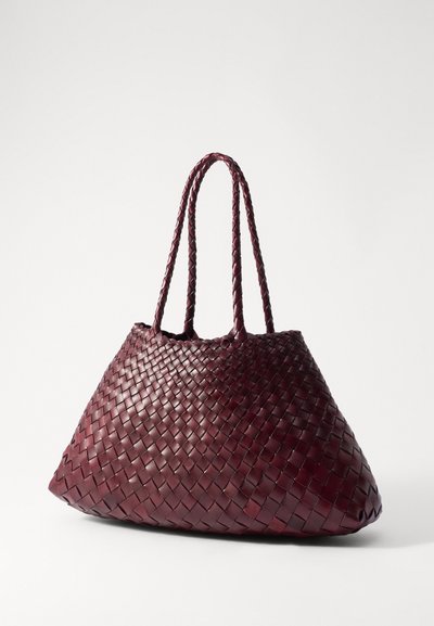 Austa austā ādas soma tumšā burgundijā, ar divām pītām rokturiem un plašu, strukturētu formu bez redzamiem piederumiem.