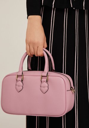 Sac à main en cuir rose avec poignées arrondies, quincaillerie dorée, fermeture à glissière, surface légèrement texturée et accents décoratifs sur les côtés.