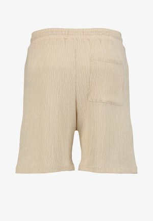 Beżowe, pomarszczone szorty z tkaniny z elastycznym paskiem w talii i pojedynczą naszywaną kieszenią po prawej stronie.