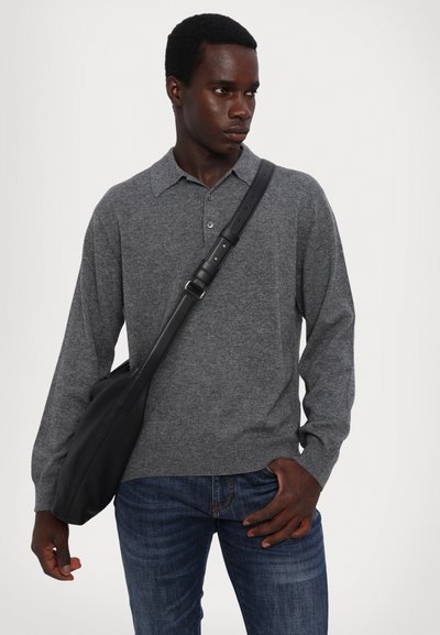 Grauer Strick-Polo-Pullover mit einem Kragenhals, kombiniert mit dunkelblauen Jeans und einer strukturierten schwarzen Schultertasche.