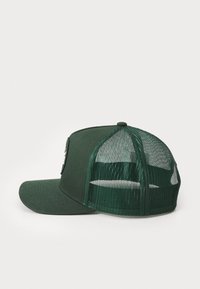 Cappello verde con un pannello frontale solido e retro in rete. Presenta una visiera curva e una toppa con logo sulla parte anteriore. Motivo testurizzato sulla rete.