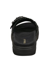 Sandale noire avec une semelle épaisse et rembourrée, dotée d'une sangle texturée avec des accents métalliques et d'une boucle ajustable à l'arrière.