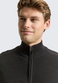 Dunkelgrauer Reißverschluss-Pullover mit hohem Kragen, strukturiertem Rippstoff und einem halben Reißverschluss vorne. Schlichtes, figurbetontes Design.