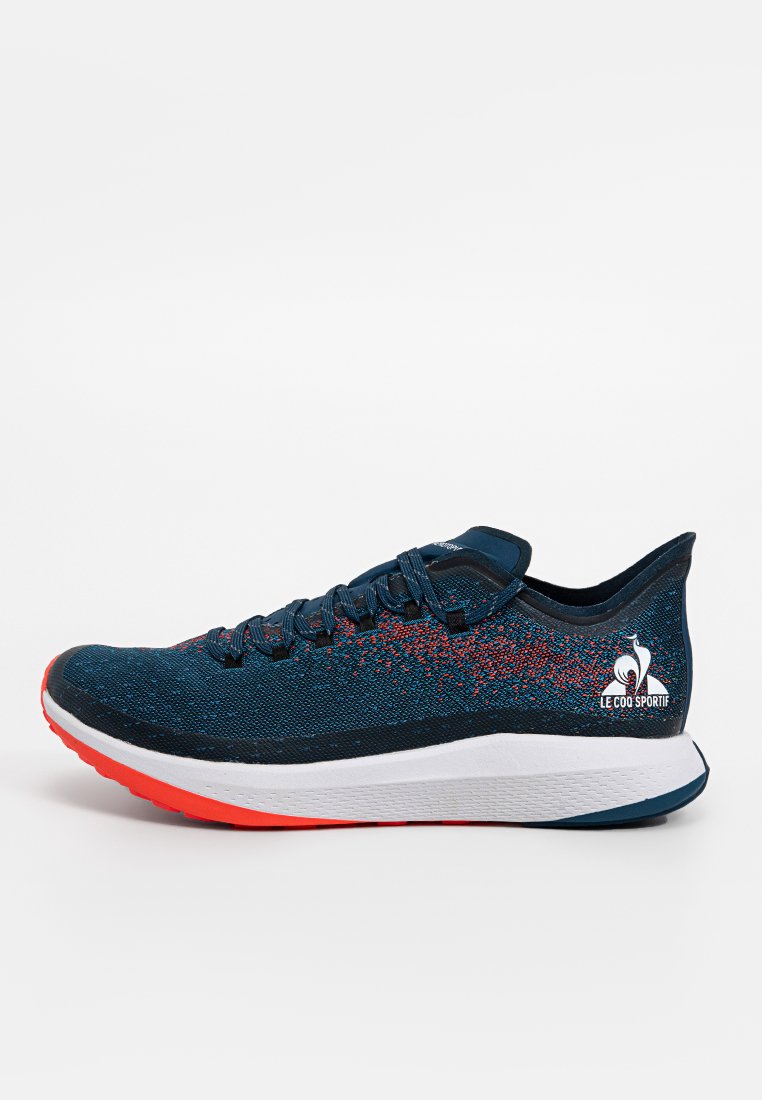 Baskets en maille bleu foncé avec des accents rouges, dotées d'un intercalaire blanc et d'une semelle extérieure texturée. Comprend un logo sur le côté.