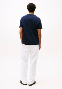 T-shirt in cotone blu navy con scollatura rotonda classica e maniche corte, abbinato a pantaloni bianchi. Design semplice, vestibilità ampia, senza motivi visibili.