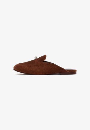 Mule marrone in suede senza lacci, con suola piatta e piccolo dettaglio di fibbia argentata sulla tomaia.