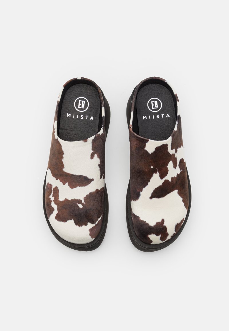 Schwarz-braun und weiß geflecktes Slip-On-Schuhe mit einer gepolsterten schwarzen Innensohle und einer langlebigen schwarzen Außensohle, gefertigt aus weichem, wildlederähnlichem Material.