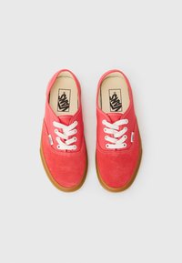 Red canvas lace-up shoes with white laces, brown rubber soles, and a logo on the side. Features a smooth texture and rounded shape.