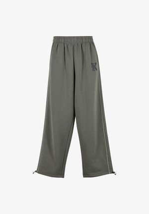 Luźne spodnie dresowe w oliwkowym kolorze ze ściągaczem w pasie, małym czarnym logo "K" na lewej udzie oraz regulowanymi sznurkami przy nogawkach.