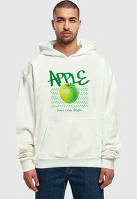 Felpa bianca con un grafico di una mela verde con la scritta "APPLE" in bold verde e "Dolce. Croccante. Semplice." in un testo più piccolo sotto.