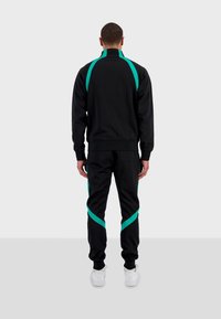 Černá atletická tepláková souprava s tyrkysovými akcenty, obsahující bundu na zip a zúžené kalhoty, vyrobená z hladké látky.