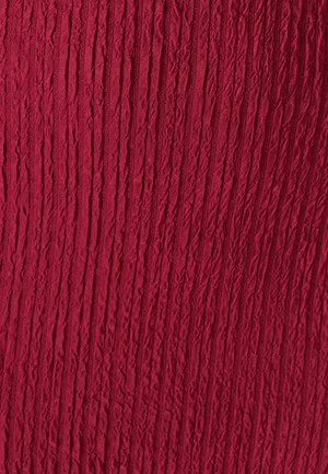 Červená textúrovaná tkanina s vertikálnymi zvlnenými pruhmi. Povrch pôsobí pokrčeným dojmom, čo materiálu pridáva hmatovú kvalitu.