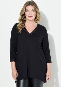 Zwart long-sleeve top met een V-hals, versierd met kanten rand langs de hals en mouwen, gemaakt van een zachte, lichte stof.