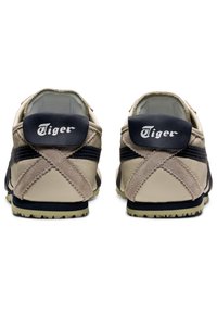 Beige and navy shoes with rubber soles, featuring a textured finish, cross-stitching detail on the back, and "Tiger" branding on the heel.