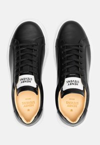 Black leather sneakers with a smooth texture, white rubber sole, and padded tongue. Features laces and branding on the tongue.