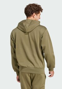 Olivovo zelená mikina s kapucňou z textúrovanej látky. Má voľný strih, rebrované manžety a klokanie vrecko. Pohľad zozadu.
