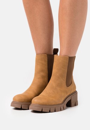 Stivaletti alla caviglia color marrone, realizzati in pelle liscia, con pannelli laterali elastici, suole in gomma chunky e punta arrotondata.