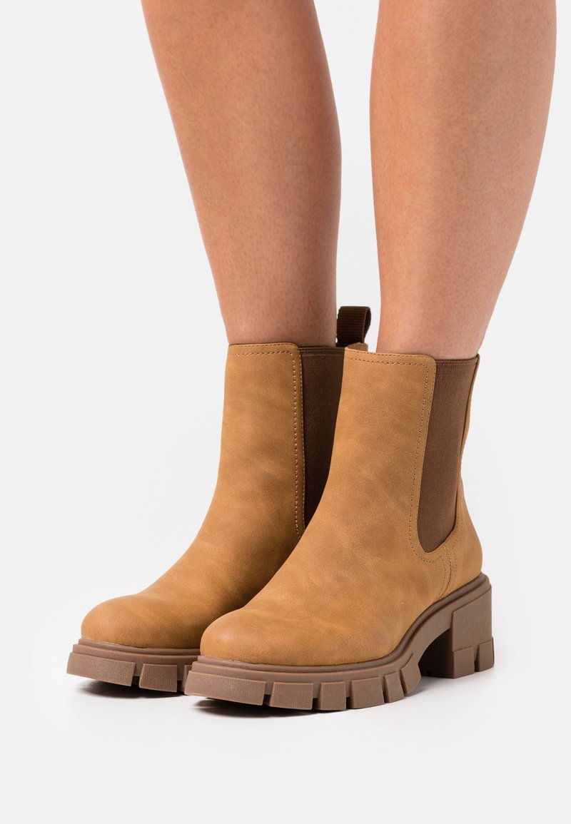 Stivaletti alla caviglia color marrone, realizzati in pelle liscia, con pannelli laterali elastici, suole in gomma chunky e punta arrotondata.