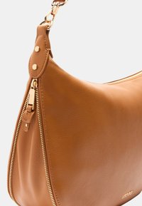 Borsa a spalla in pelle marrone con una superficie liscia, forma curvata, accessori in oro e dettaglio con zip sul lato.