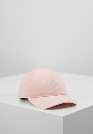 Casquette de baseball rose clair avec le logo "LEVI'S" blanc brodé à l'avant, posée sur une surface blanche avec un fond uni.