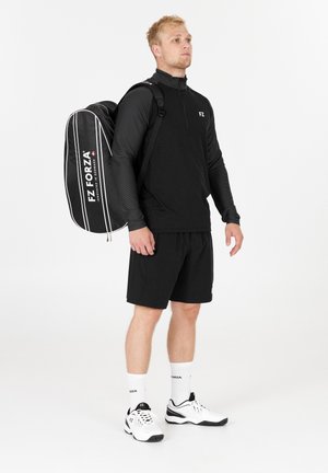 Sorte quarter-zip langærmet top, matchende shorts og hvide træningssko. Sort rygsæk med hvide striber og logo. Minimalistisk design.